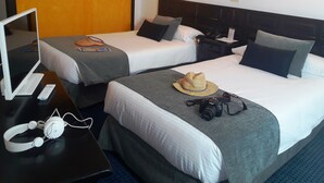 A hotel room with two beds, a desk with a laptop and headphones, and a hat on one bed. - Hotel Miramar (Arrecife)