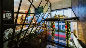 A modern interior with a glass staircase, a Christmas tree, and a reception area. - Hotel Miramar (Arrecife)
