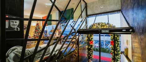Un interior moderno con una escalera de cristal, un árbol de Navidad y una zona de recepción.