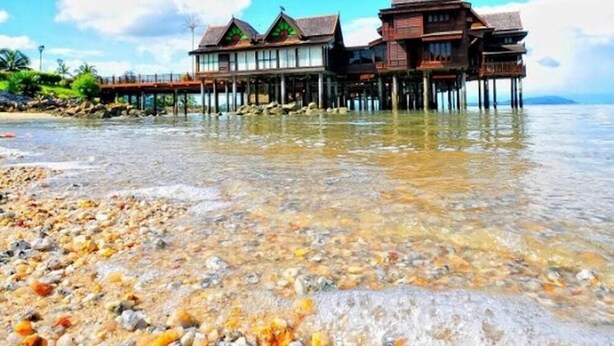 A beachfront property with wooden structures over water, clear skies, and a pebble beach. - Langkawi Lagoon Resort (Langkawi)