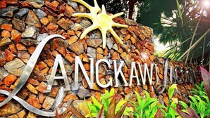 A stone wall with the name 'LANCKAWILACUM' in large letters, a sun-shaped decoration, and tropical plants in front. - Langkawi Lagoon Resort (Langkawi)