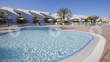 Een buitenzwembad, parasols bij het zwembad en ligstoelen