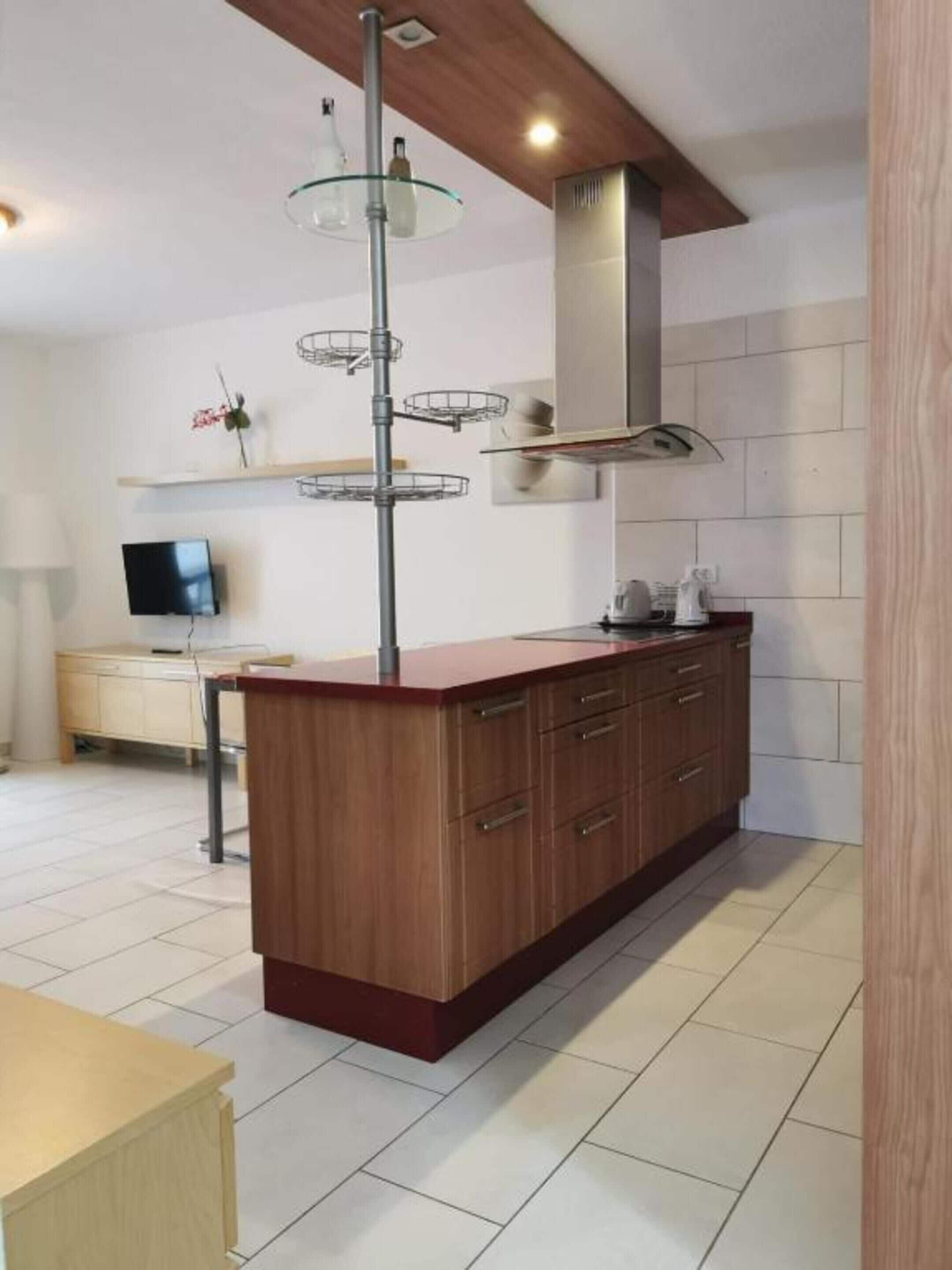 A modern kitchen with a wooden island, a glass pendant light, and a built-in stove.