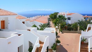 Un hôtel situé sur la côte, avec des bâtiments blancs, des toits en tuiles de terre cuite et une vue sur la mer.
