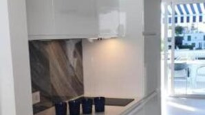 Une cuisine moderne avec des meubles blancs, un plan de travail en bois et un four encastré.