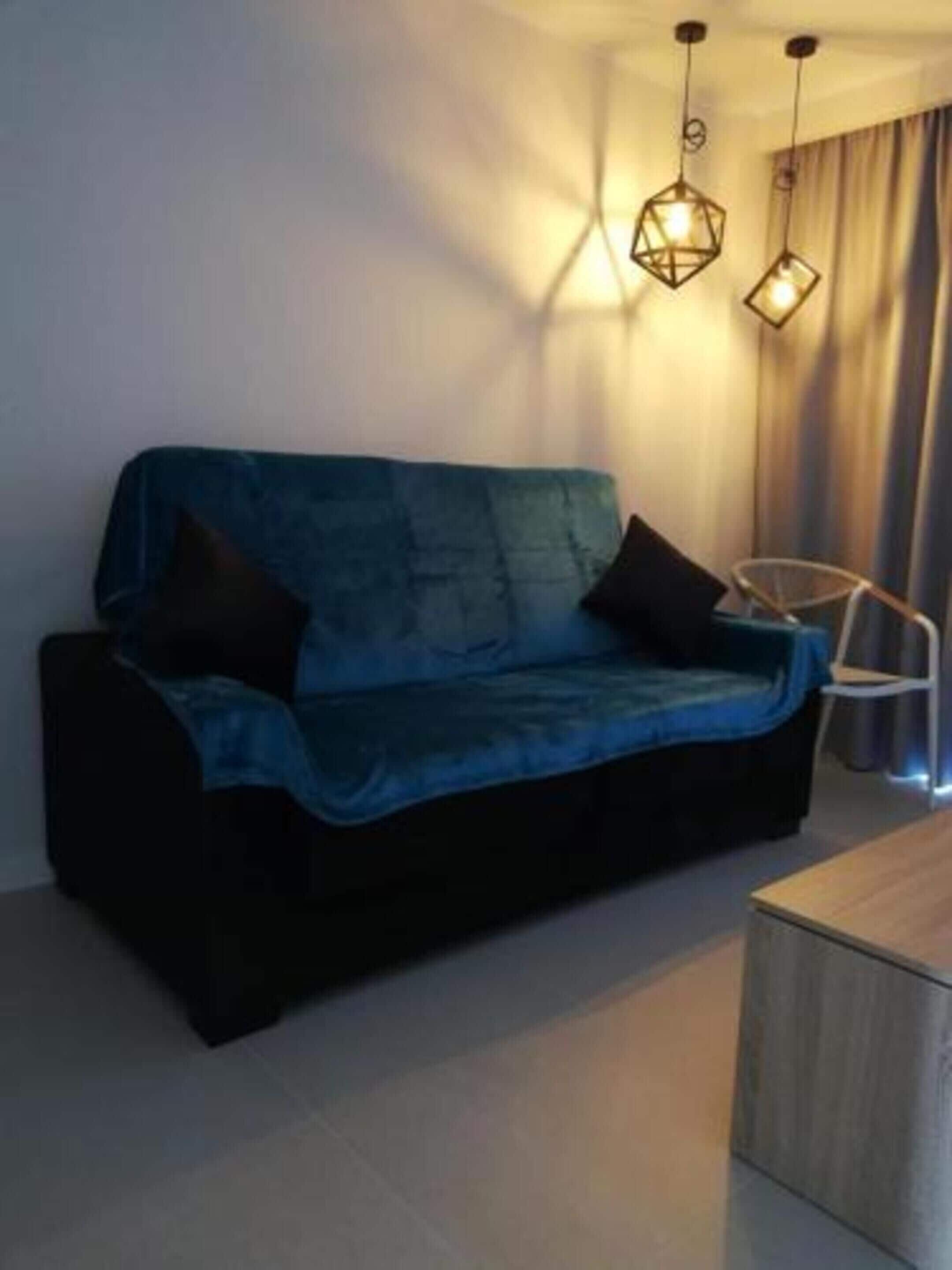 Una sala de estar moderna con un sofá azul, una mesa de centro de madera y lámparas colgantes.