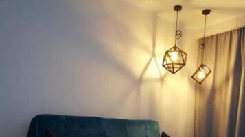 Una sala de estar moderna con un sofá azul, una mesa de centro de madera y lámparas colgantes.