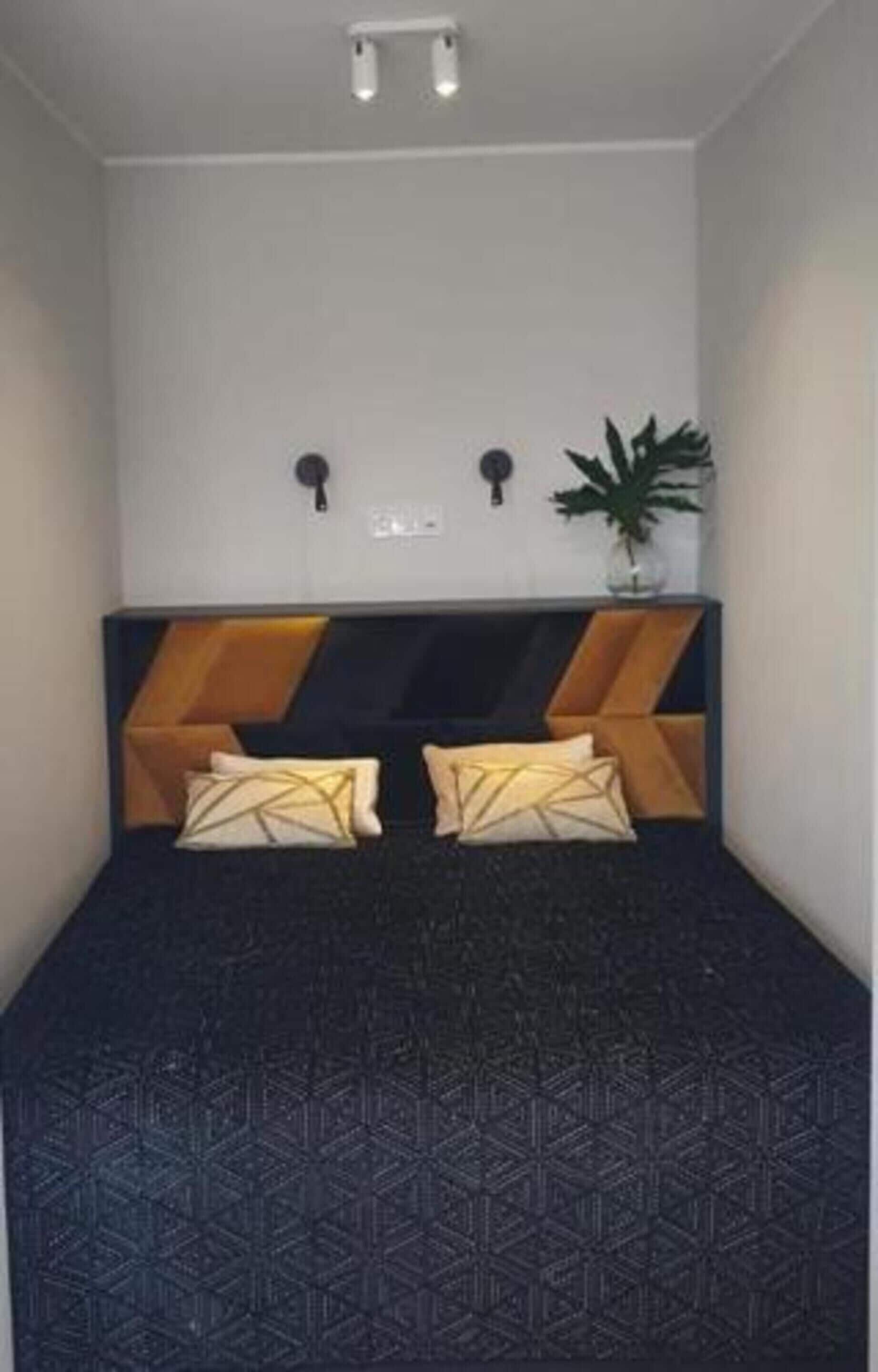 A room with a bed, two wall-mounted lamps, and a potted plant.