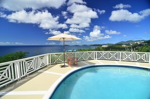 A swimming pool with a white fence, a chair, and an umbrella. - Villa Marbella Suites (St. Thomas)