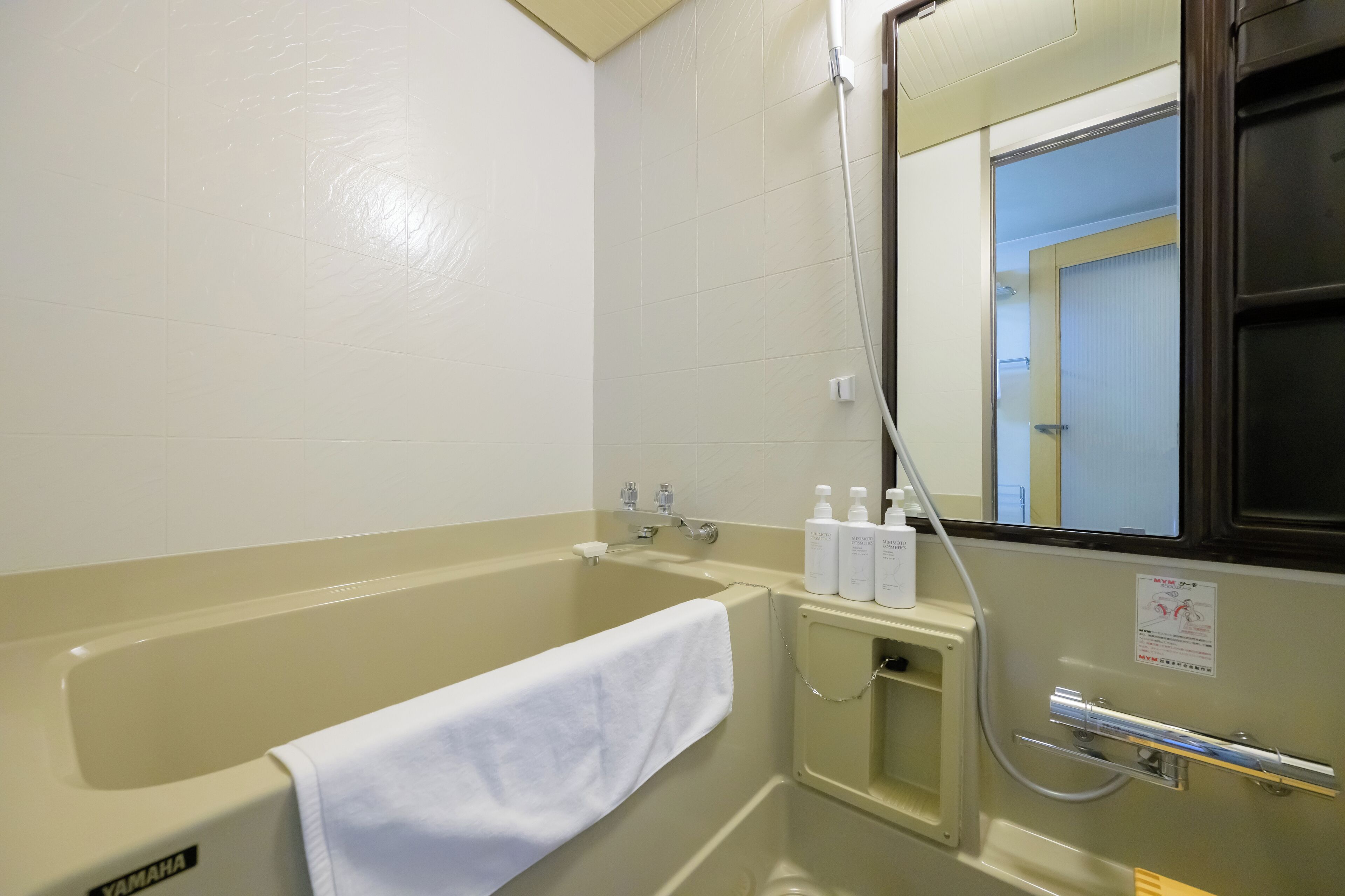 A bathroom with a bathtub, a towel, and toiletries.