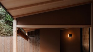 Un espacio al aire libre techado con muebles de madera y una pequeña mesa, un banco de madera y una lámpara fijada a la pared.