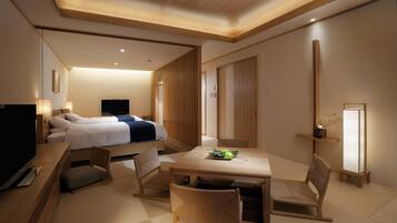 A modern hotel room with a bed, a desk, a chair, a TV, and a bedside table.