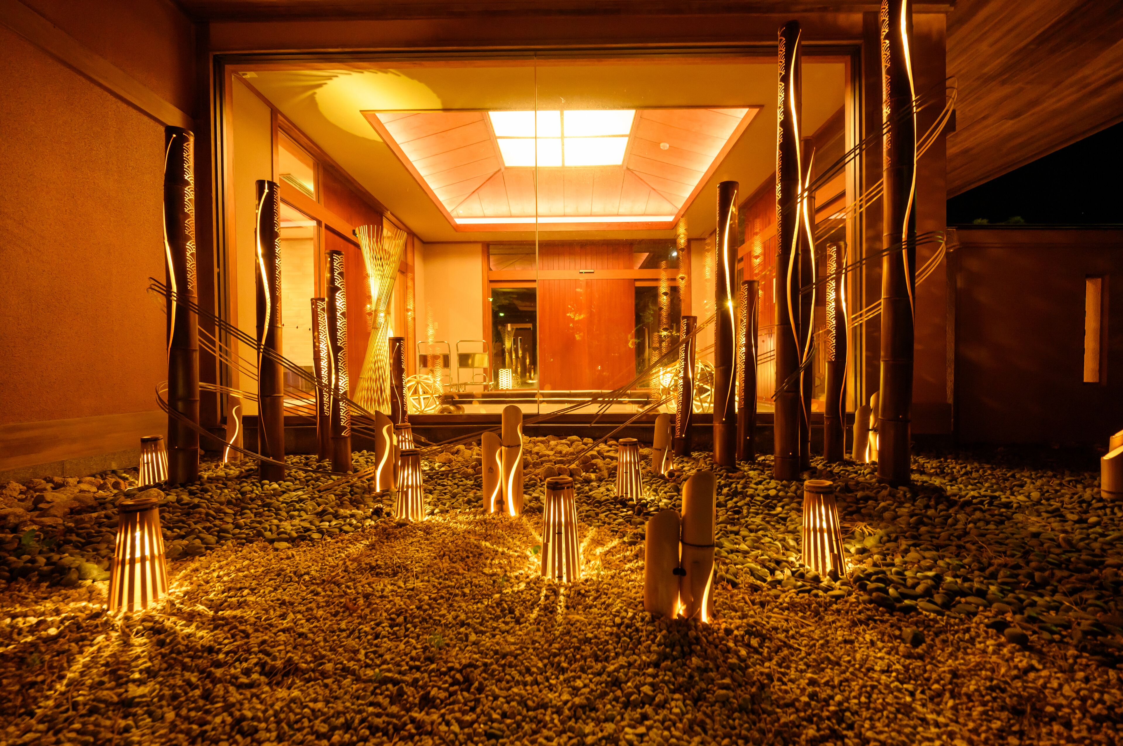 Un vestíbulo de hotel con un área de estar central, una escalera y un gran techo iluminado.