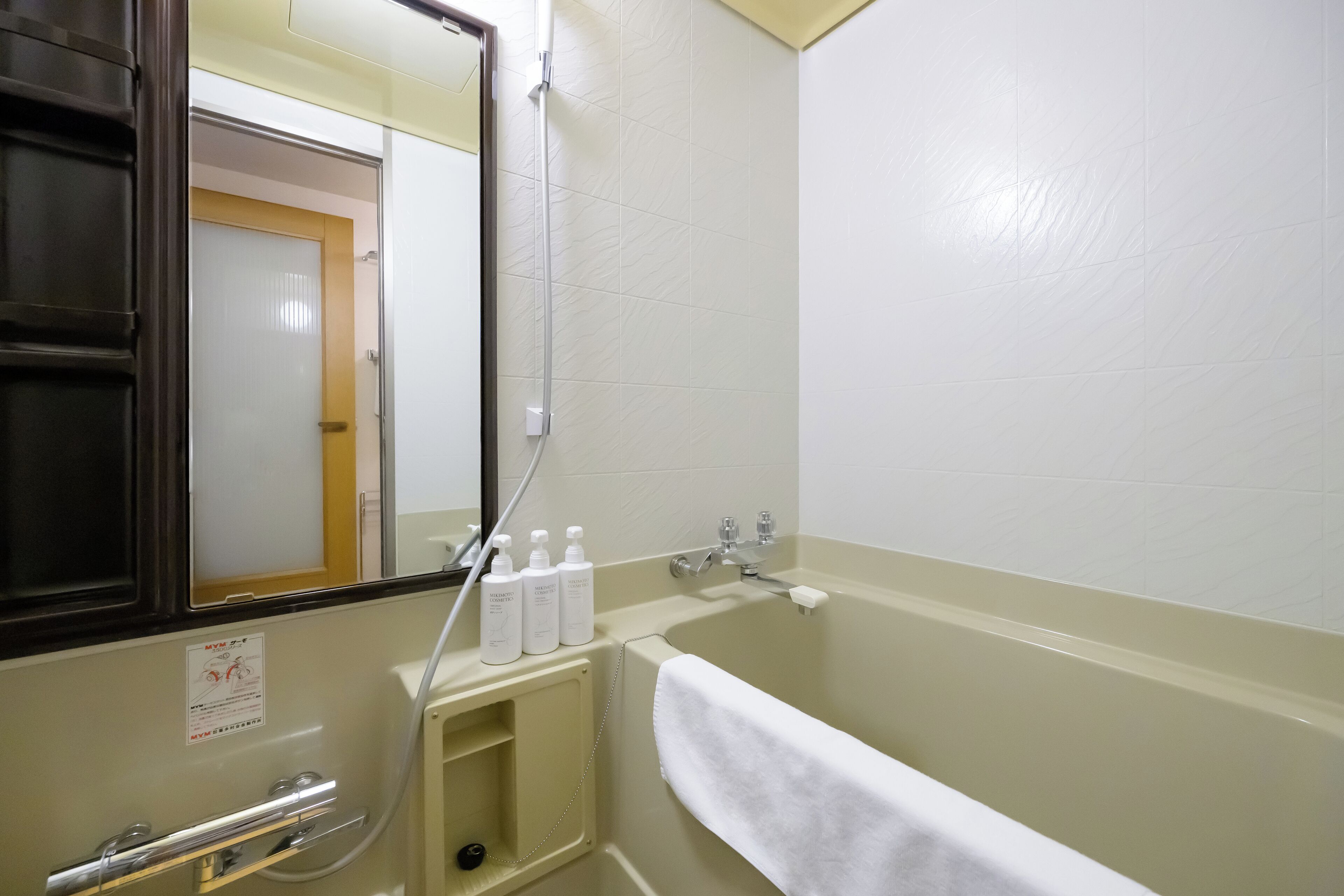 A bathroom with a bathtub, a mirror, and a towel rack.