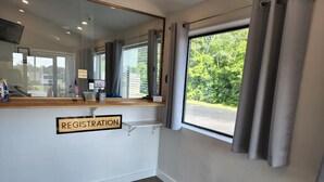 A registration desk with a sign, a mirror, and a window with curtains.