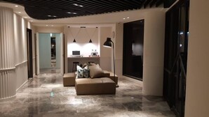Een modern interieur met een gebogen muur, een bank, hanglampen en een groot raam.