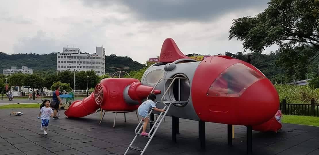 A playground with a red and gray rocket-shaped play structure.