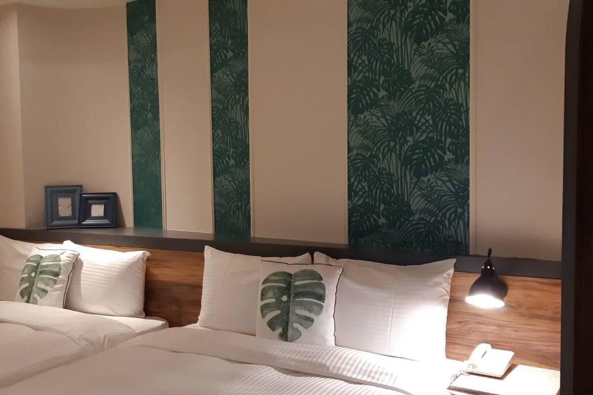 Une chambre d’hôtel avec un lit, une table de chevet avec une lampe et un téléphone.