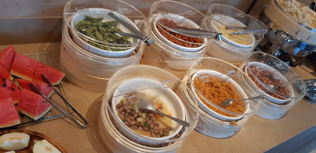 Een buffet met diverse gerechten, waaronder watermeloen, groene bonen en verschillende soorten bonen en granen.