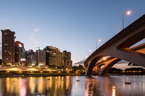 A cityscape with a river, a bridge, and illuminated buildings.