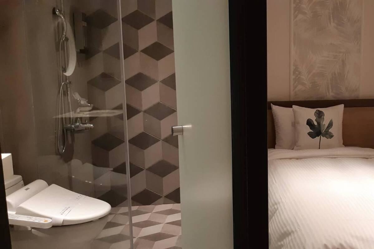 Une chambre d’hôtel avec une douche, des toilettes et deux lits avec des oreillers assortis.