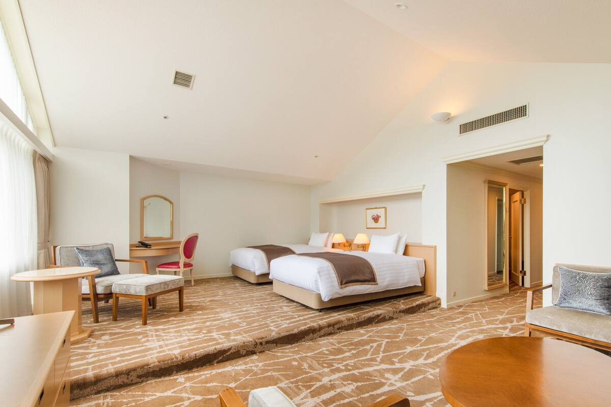 A hotel room with a bed, two bedside tables, a desk, a chair, and a small table.