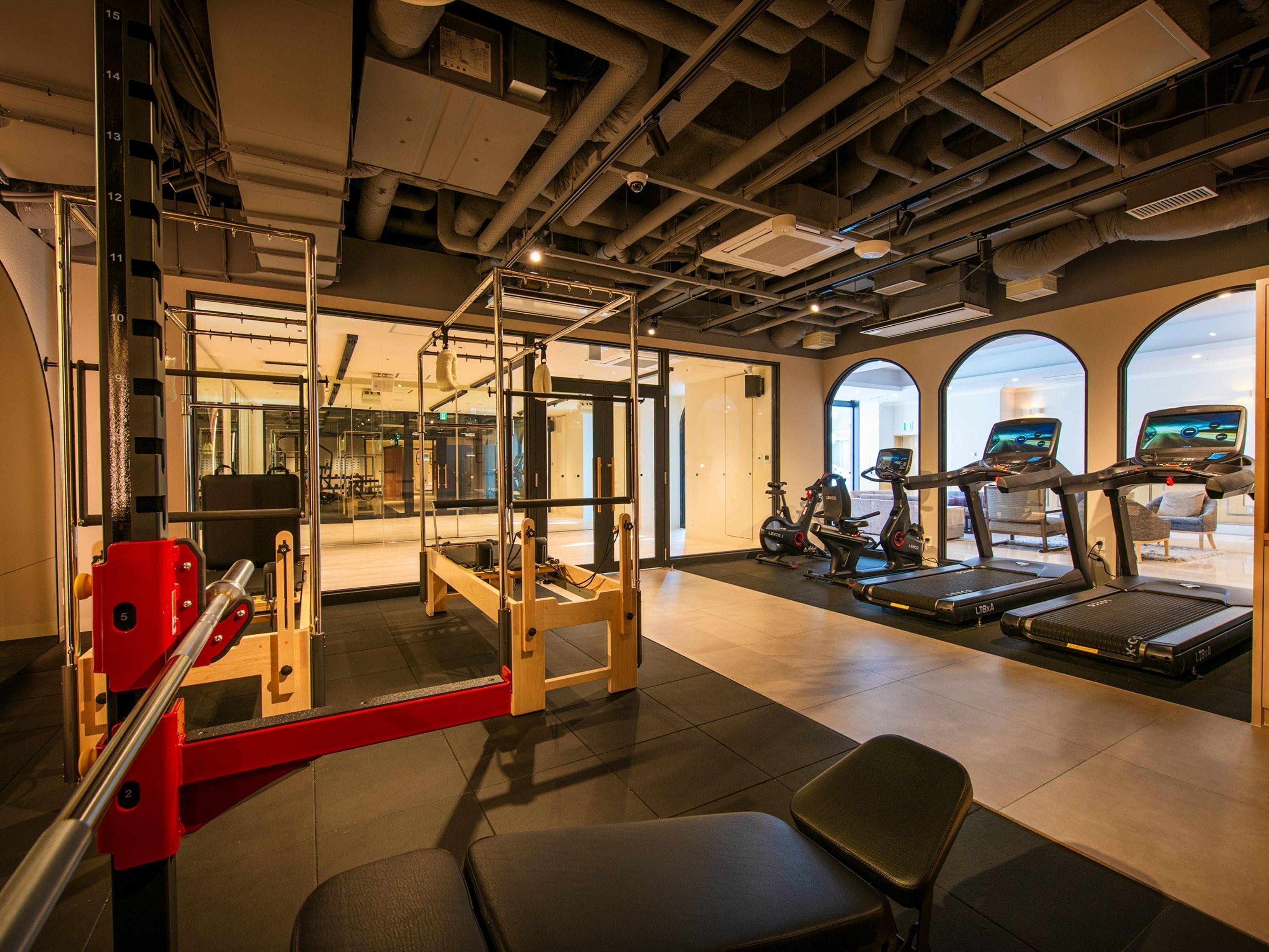 A gym with exercise equipment, a mirror, and a view of the outside.