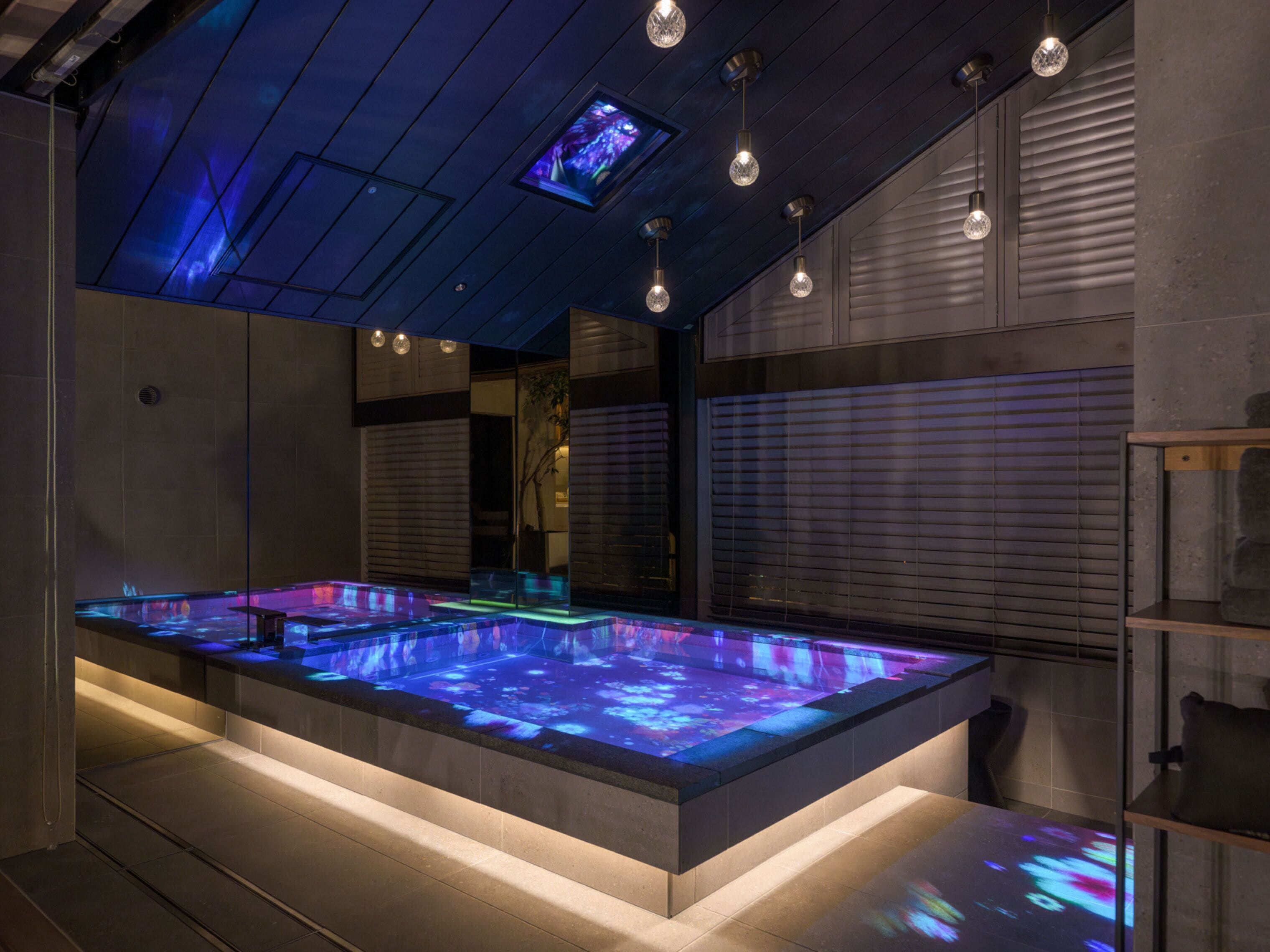 Un espacio de spa moderno con suelo calefaccionado, luces en el techo y un espejo grande.