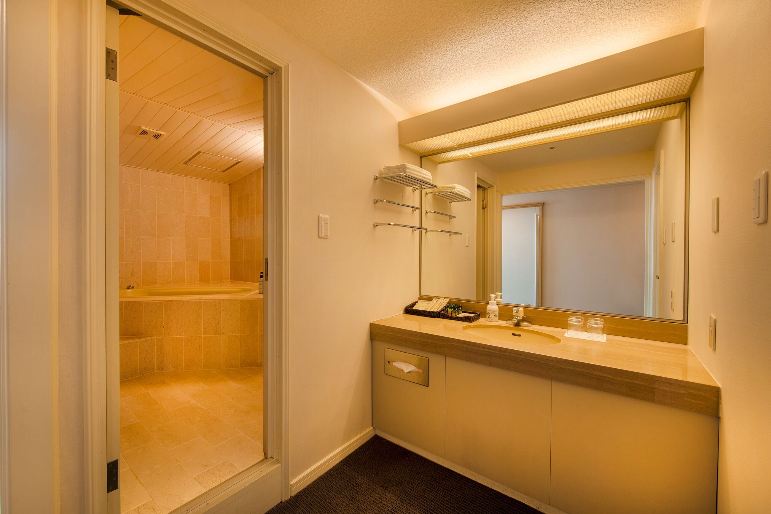 A bathroom with a bathtub, a sink, a mirror, and towel racks.