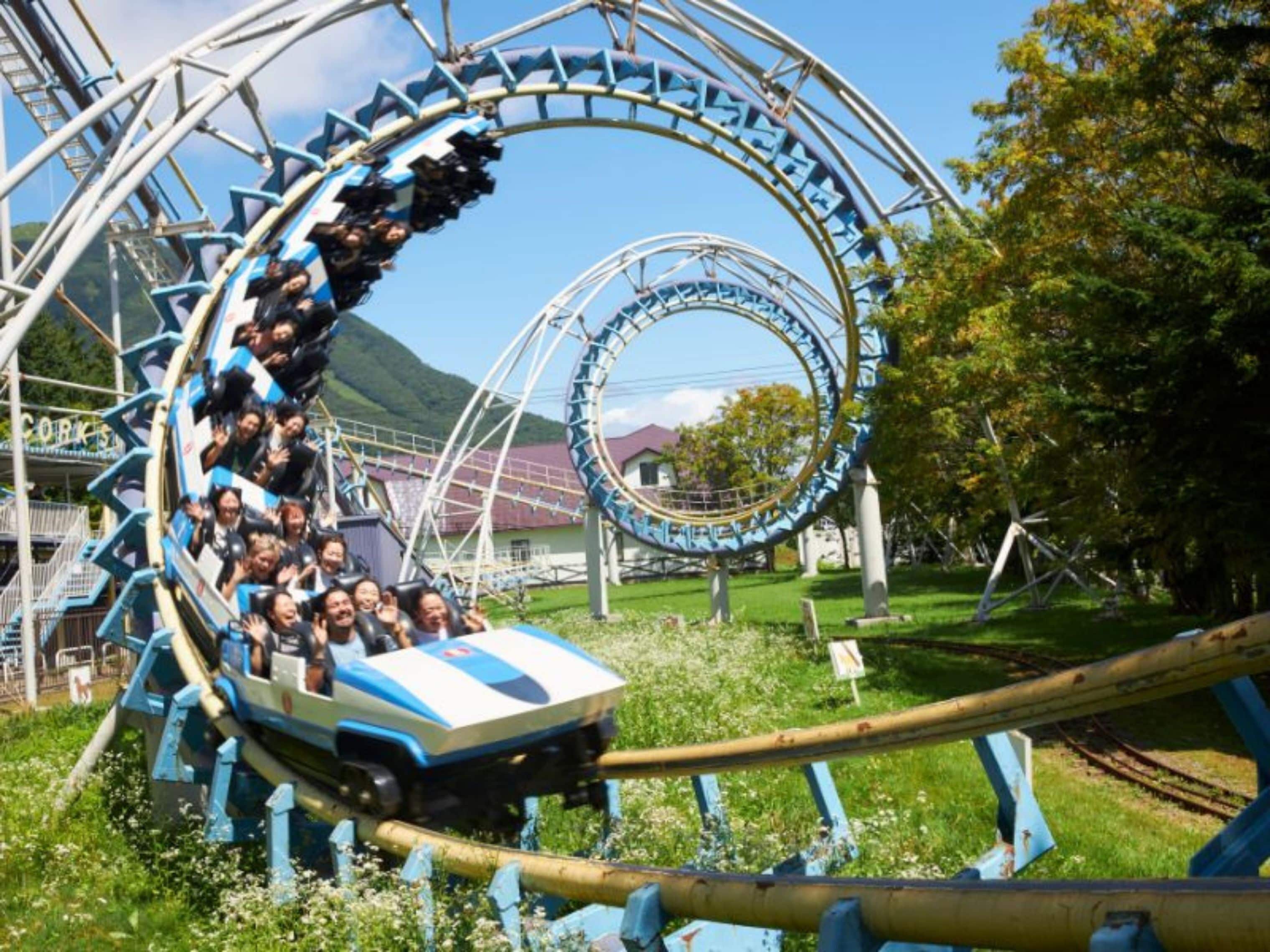 Eine Achterbahn in einem Park mit Blick auf ein Bergpanorama.