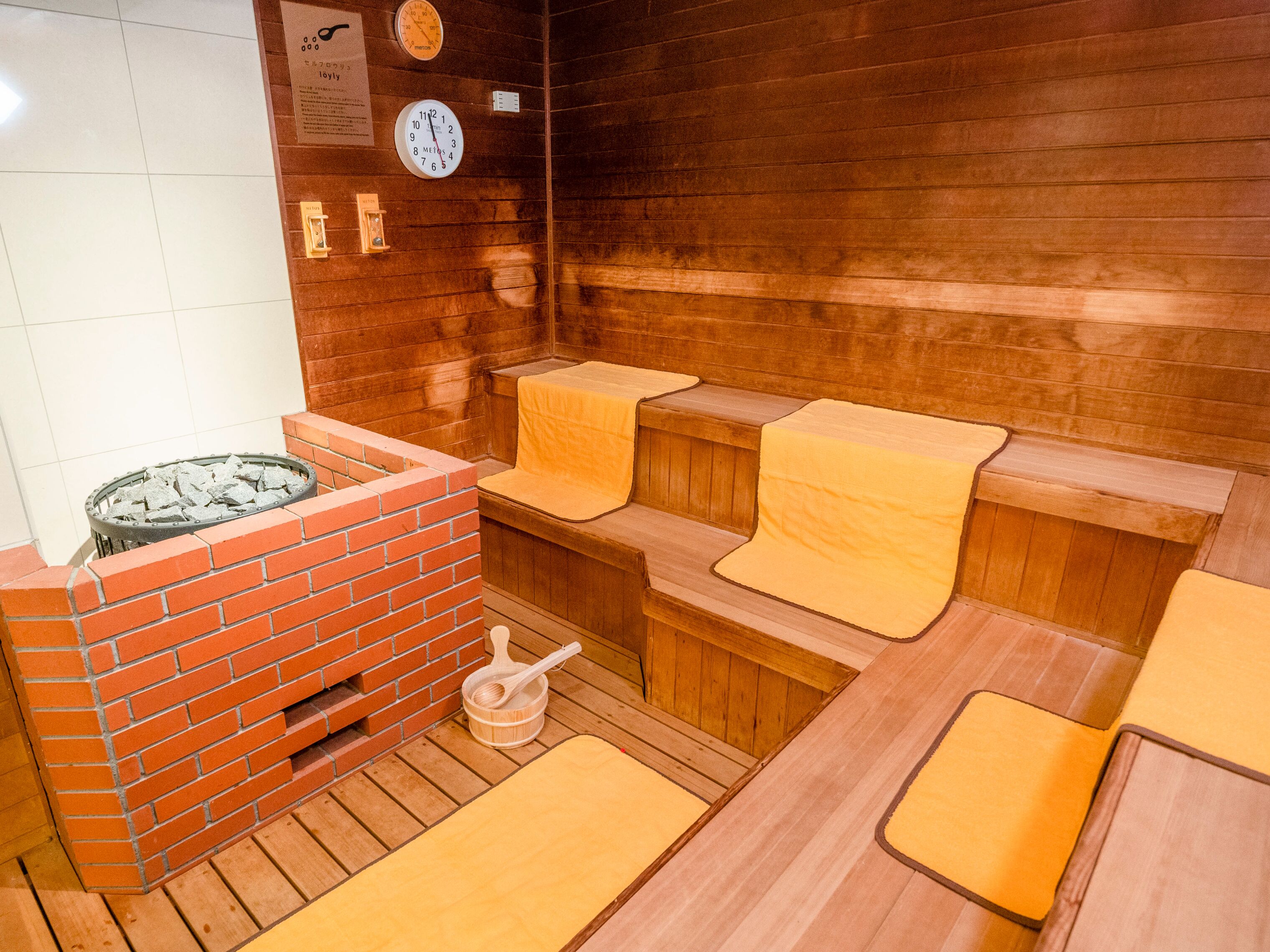 A sauna with wooden benches and a brick heater.
