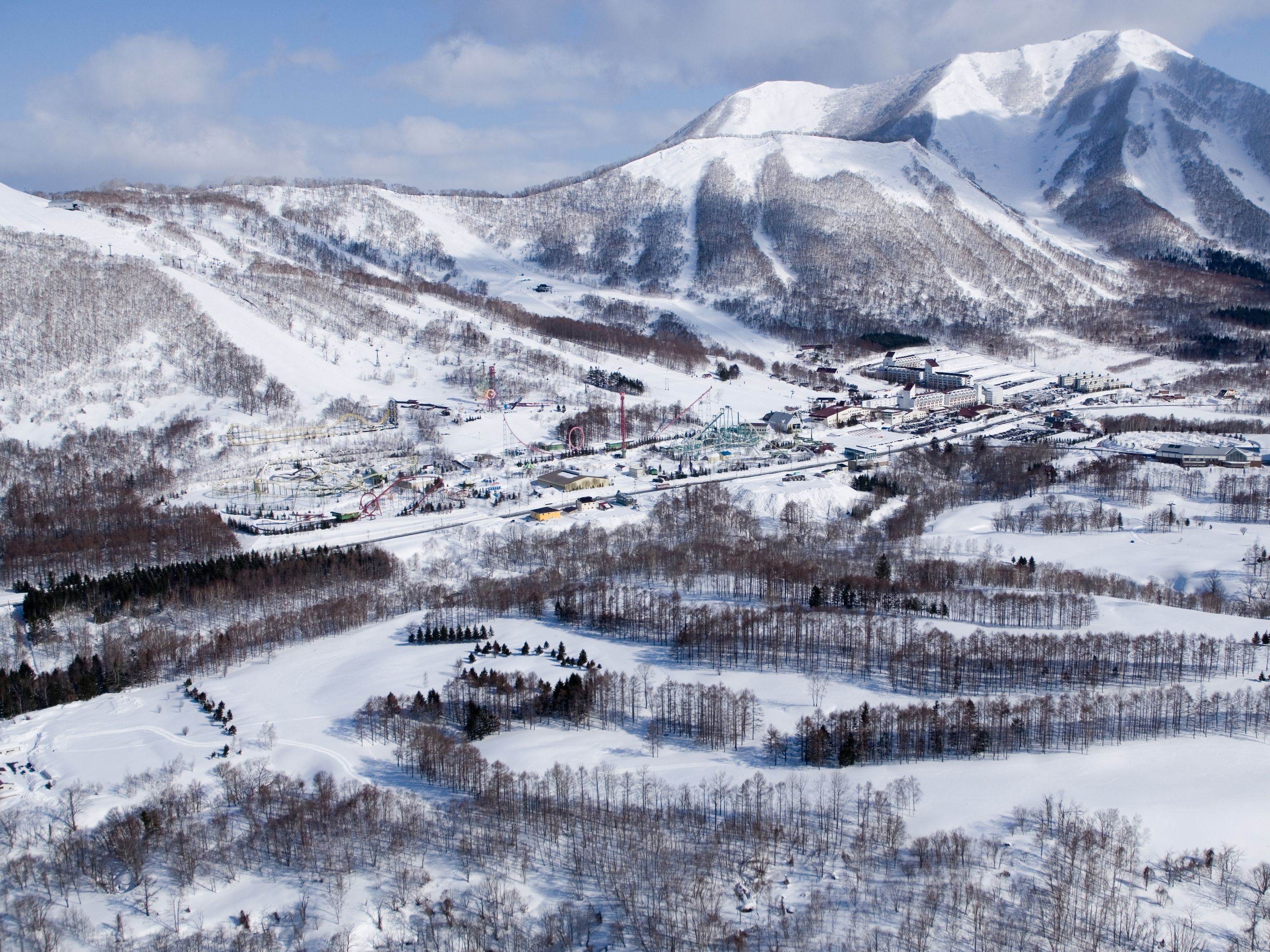 Une ville de montagne enneigée, avec des pistes de ski, des bâtiments et un ciel dégagé.