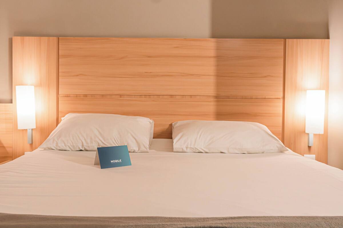A neatly made bed with a blue sign, wooden headboard, and two bedside lamps.