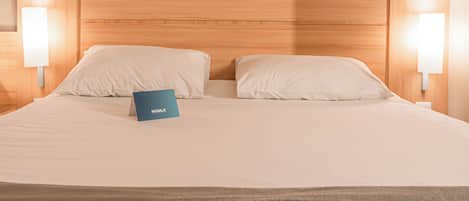 A neatly made bed with a blue sign, wooden headboard, and two bedside lamps.