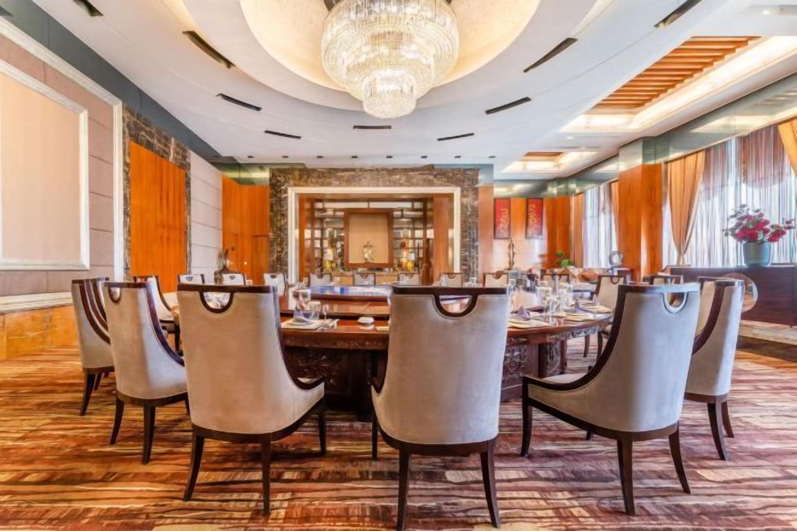 A conference room with a round table, multiple chairs, and a chandelier.