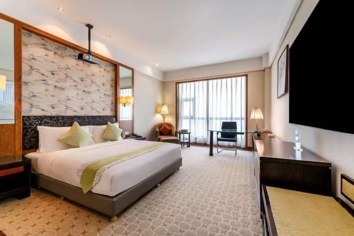 Een hotelkamer met een groot bed, een bureau, een stoel en een televisie.