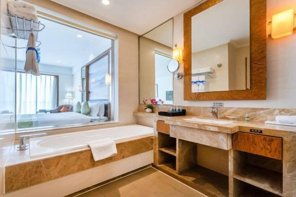 Een moderne badkamer met een groot bad, een wastafel met spiegel en een raam dat uitzicht biedt op de ruimte.