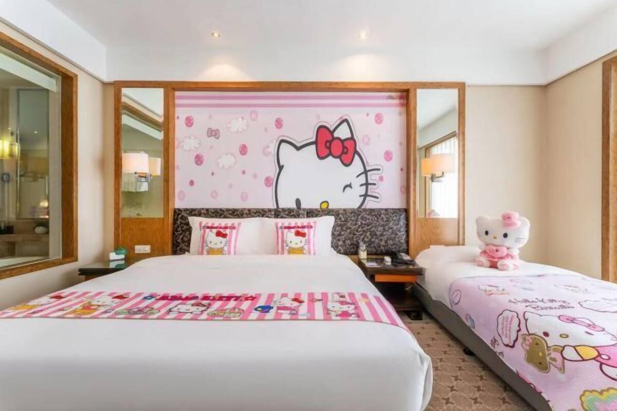 Een hotelkamer met een groot bed, een kleiner bed, een Hello Kitty decoratie aan de muur en een raam met uitzicht.