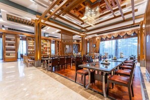 A spacious dining area with a long table and multiple chairs, surrounded by bookshelves and a chandelier. - Nishi Haitai Hotel (Weihai)