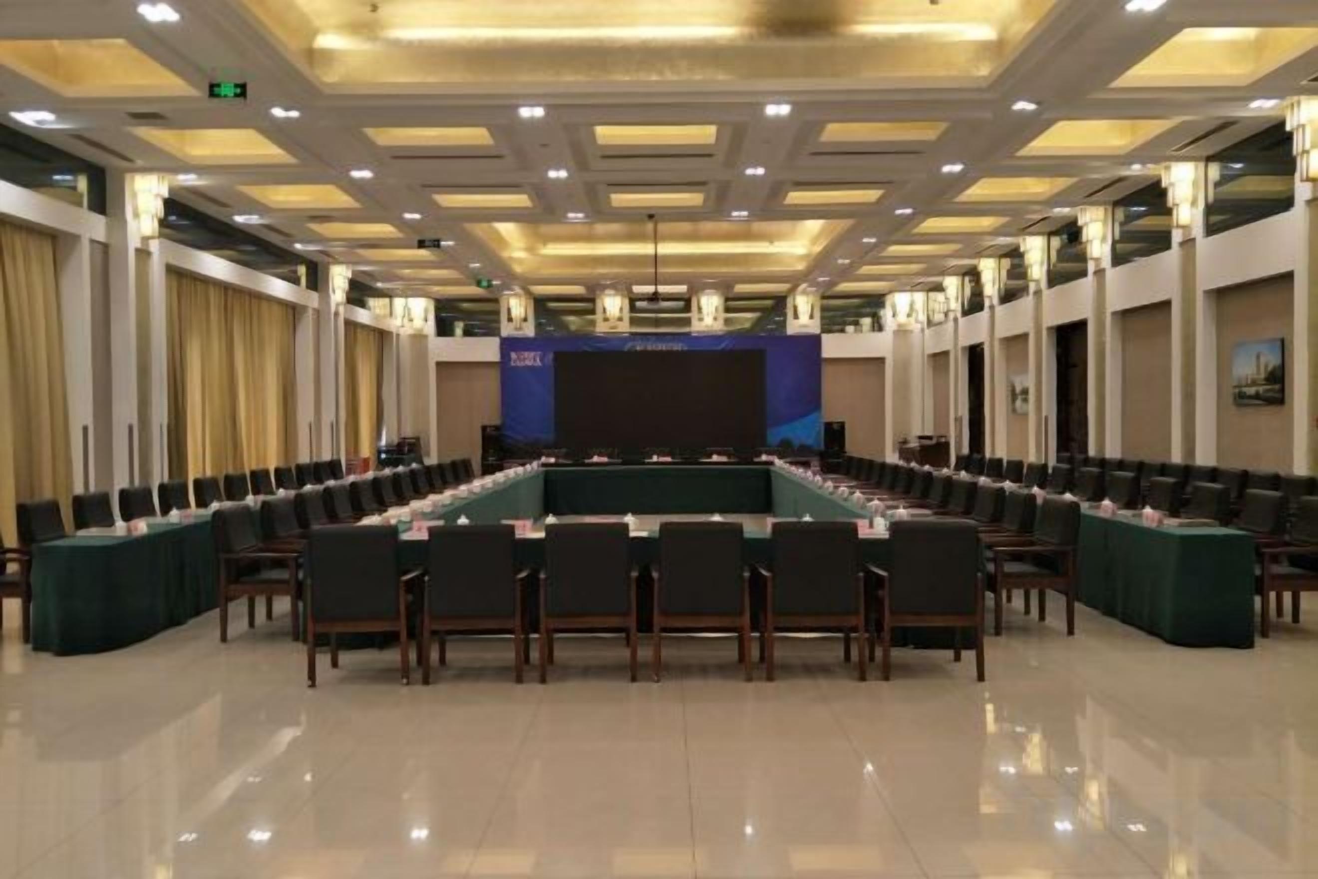 A conference room with a long table, chairs, and a stage.