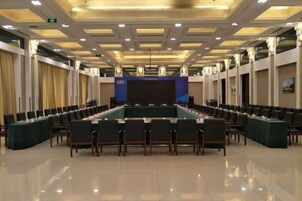 A conference room with a long table, chairs, and a stage.