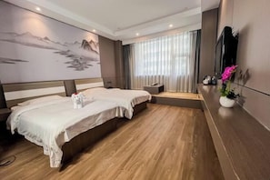 Une chambre d’hôtel avec deux lits, un grand tableau au mur, une télévision et une petite table avec une plante.