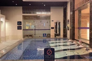 Una piscina interior con un letrero de 'prohibido el acceso', una zona de recepción y una pared de vidrio.