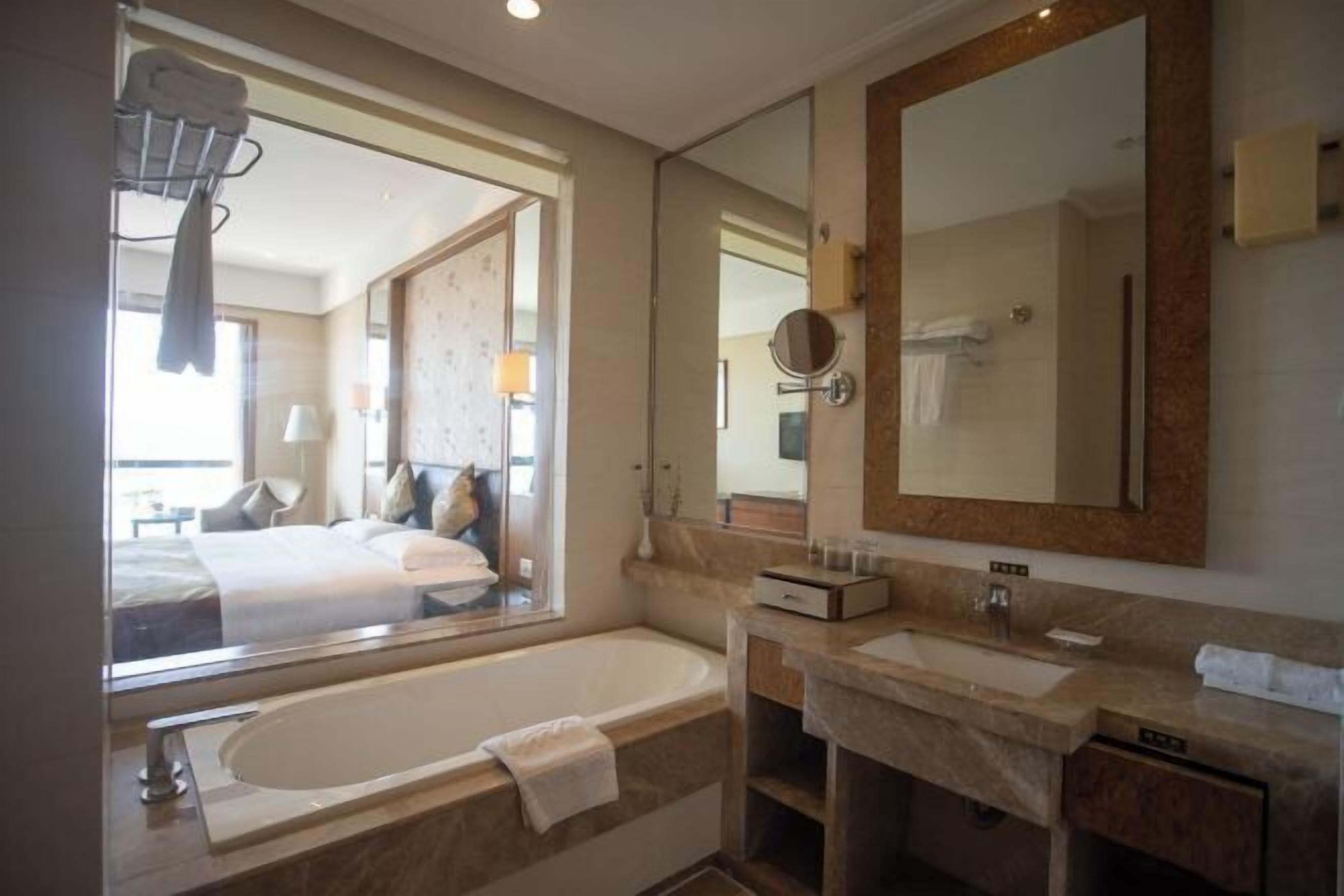 Un baño moderno con una bañera grande, un tocador con lavabo y un espejo amplio.