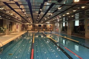 Una piscina interior con carriles delimitados, suelo de baldosas y un diseño moderno de techo con iluminación.