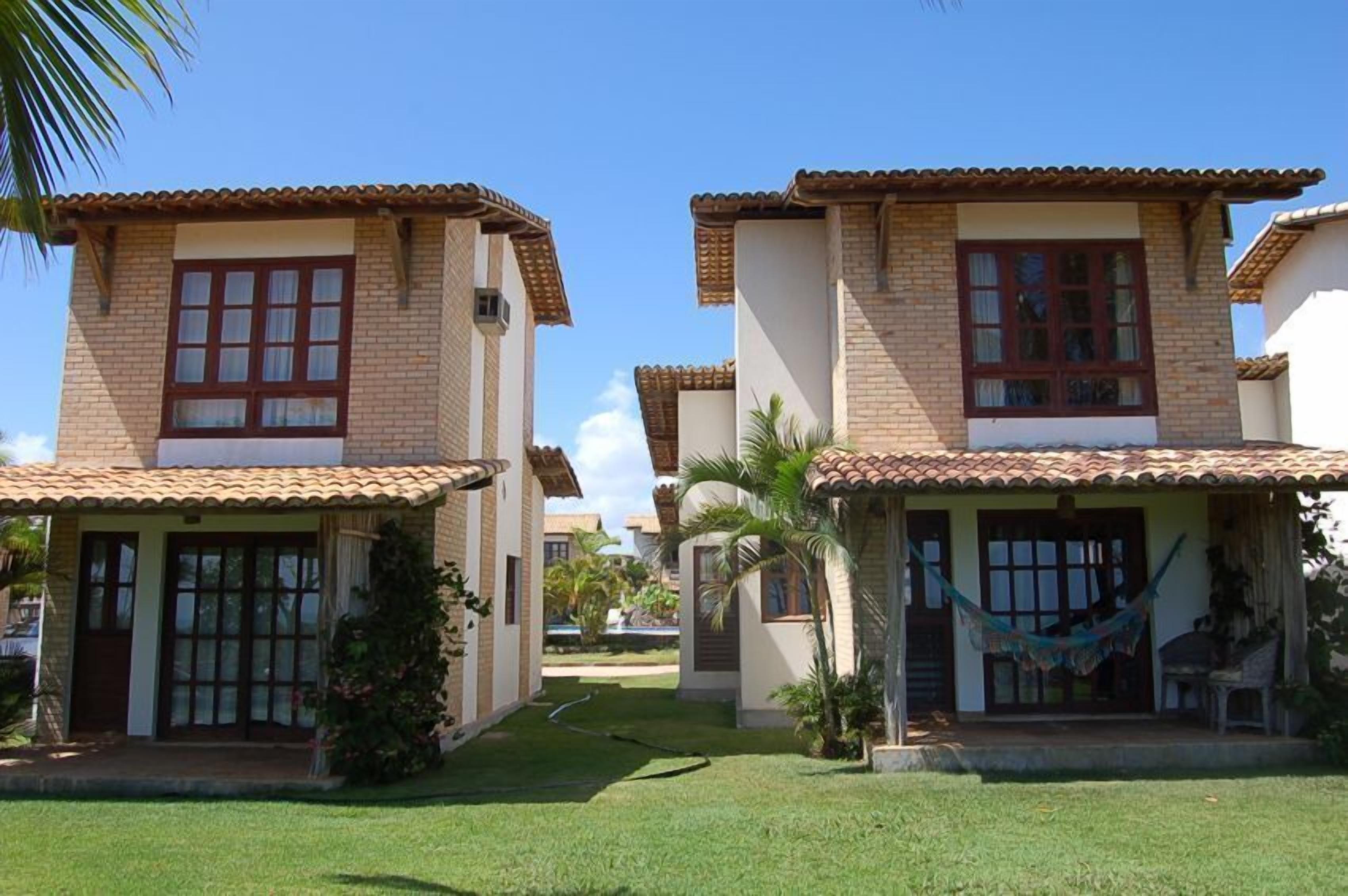 A row of two-story houses with tiled roofs, a small front porch, and a well-maintained lawn.
