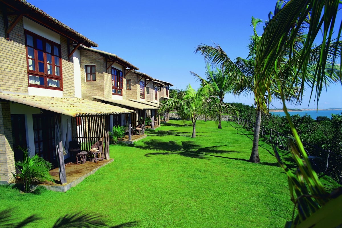 Un hotel con varias habitaciones, un césped bien cuidado y vista al océano.