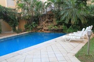 Una piscina al aire libre, sillones reclinables de piscina