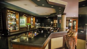 A bar area with a polished bar counter, a variety of bottles, and a seating area with chairs. - Nobile Hotel Premier Hill (Asunción)