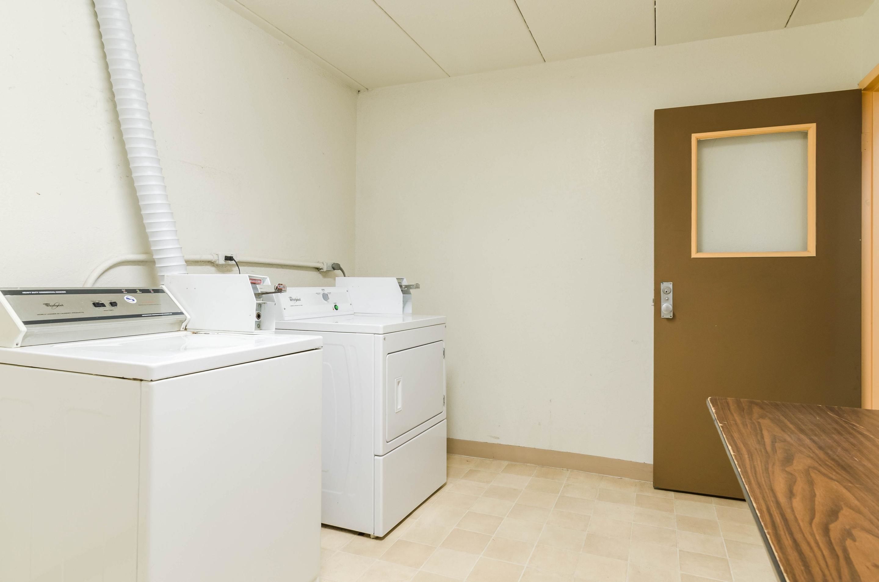 A laundry room with a washing machine, dryer, and a table.